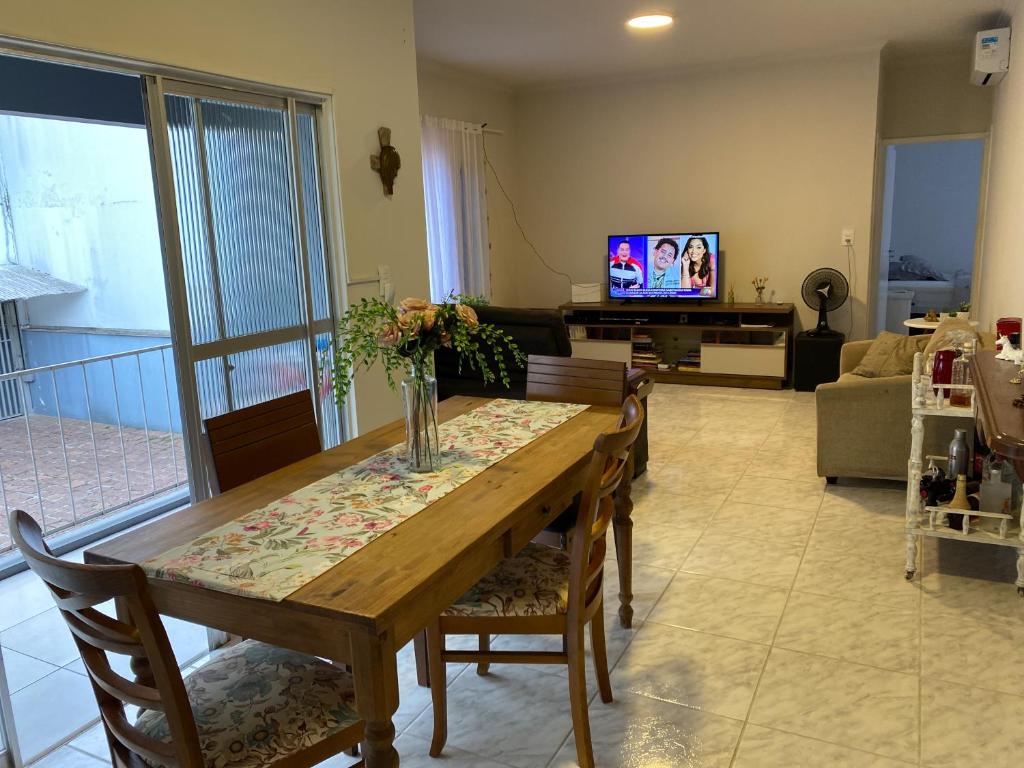 a living room with a table and chairs and a television at Quarto no Ap do Roberto Centro in Jaraguá do Sul
