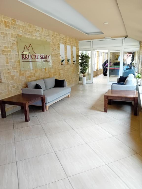 a living room with couches and tables on a tile floor at Ośrodek Konferencyjno-Wypoczynkowy "Krucze Skały" w Karpaczu in Karpacz