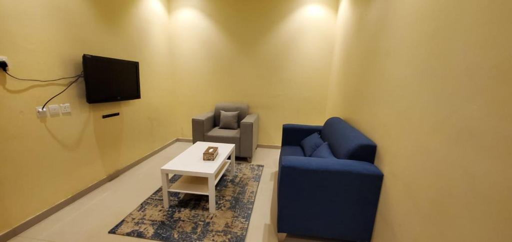 uma sala de estar com um sofá azul e uma televisão em المبيت 4 للشقق الفندقيه em Hajlah