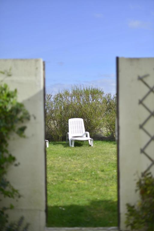 a white chair sitting in the grass in a mirror at Le Cottage de la Baie - vue mer en Baie de Somme in Woignarue