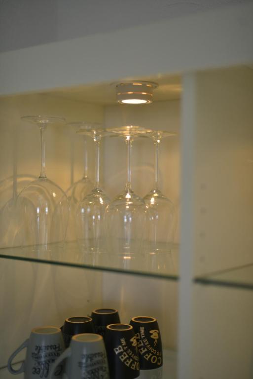 a row of wine glasses and cups on a shelf at Le Cottage de la Baie - vue mer en Baie de Somme in Woignarue