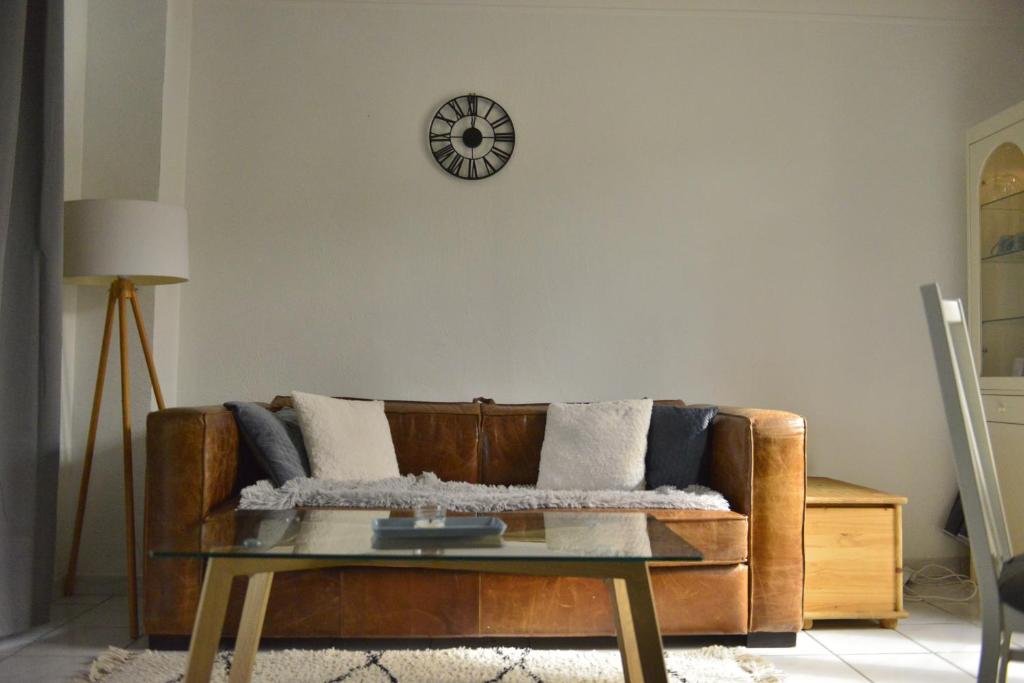a living room with a couch and a clock on the wall at Le Cottage de la Baie - vue mer en Baie de Somme in Woignarue