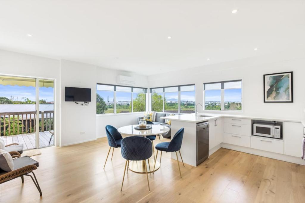 cocina y sala de estar con mesa y sillas en Sensational Rest in the North, en Auckland