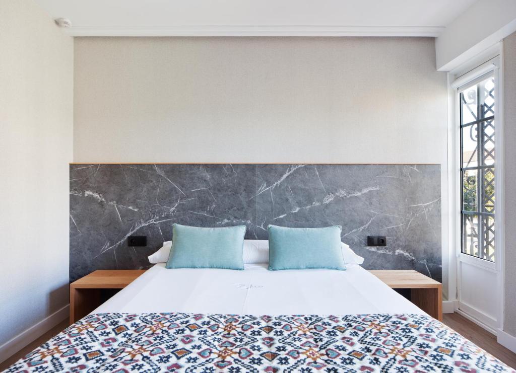 a bedroom with a large bed with blue pillows at PR 25 de Julio in Santiago de Compostela