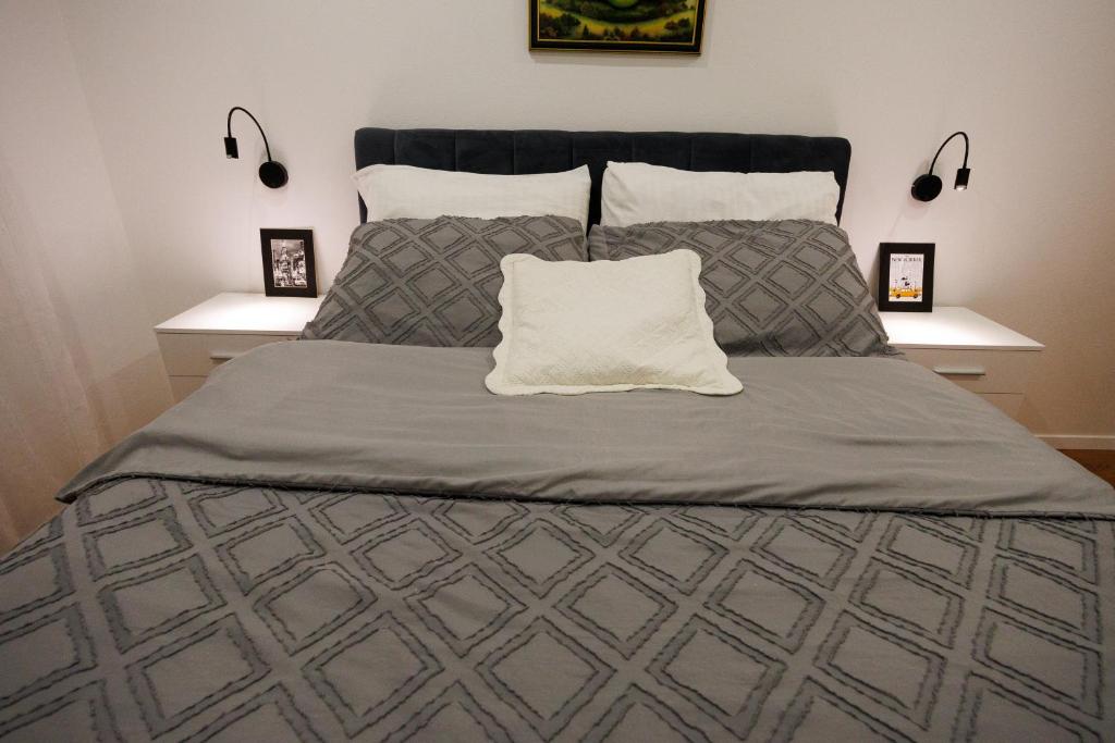 łóżko z szarą kołdrą i białą poduszką w obiekcie Apartment Nikoleto w mieście Zadar