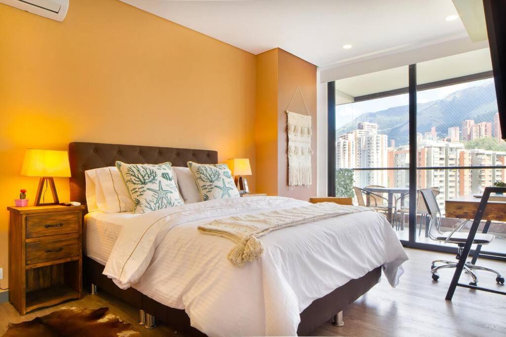 - une chambre avec un grand lit et une grande fenêtre dans l'établissement Penthouse El Poblado, hermosa vista, dos alcobas, à Medellín