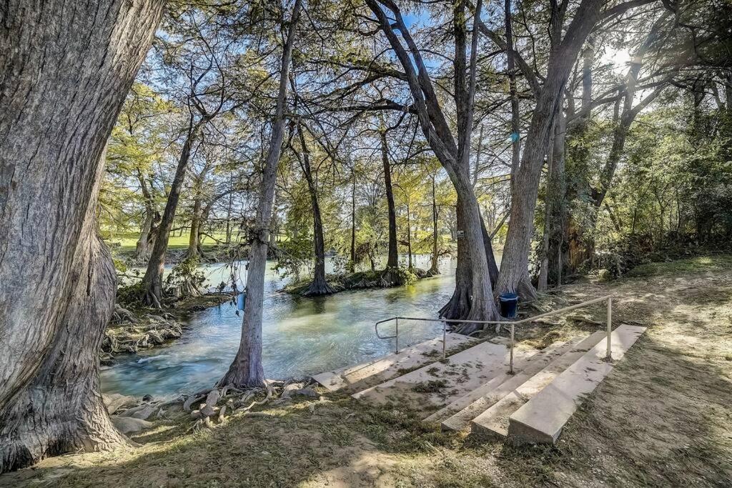 a bridge over a river in a forest with trees at Walk to Schlitterbahn, River Access & Pets OK in New Braunfels