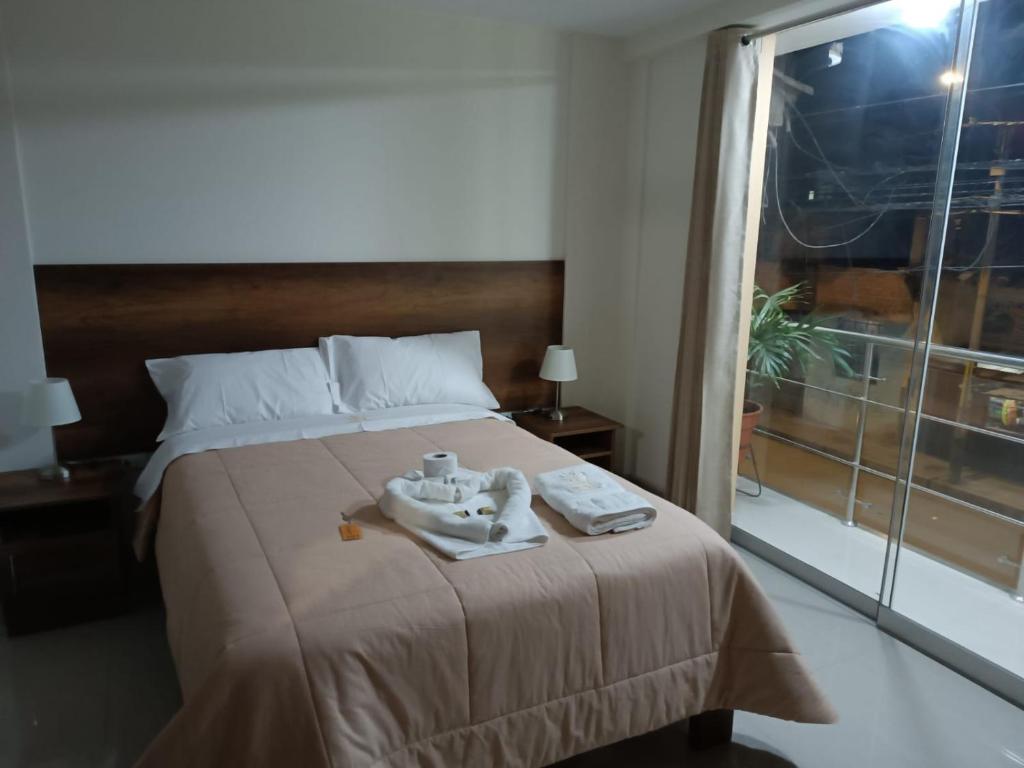 a bedroom with a bed with towels and a window at HOSPEDAJE EL EMPERADOR CAJAMARCA in Cajamarca
