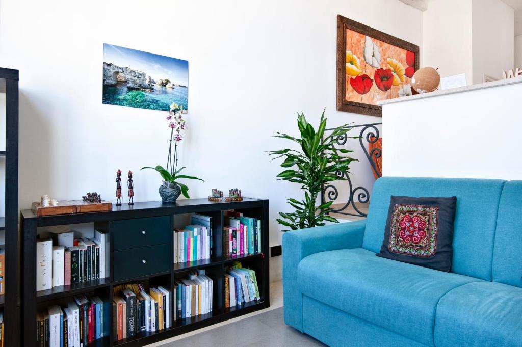 un sofá azul y una estantería con libros en The golden hour, luxury apartment with a panoramic view, en Lecce