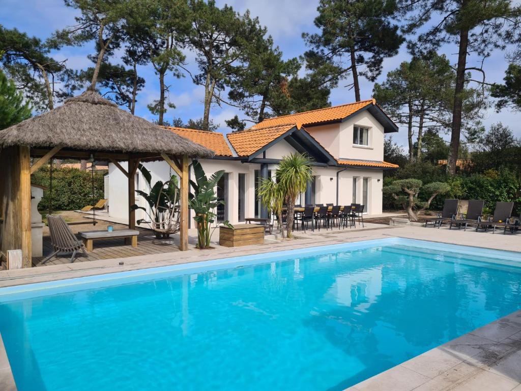 uma casa com piscina e um gazebo em VILLA PROCHE MER/PISCINE CHAUFFEE ET SECURISEE/CLIMATISATION em Lacanau-Océan