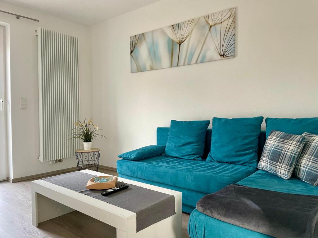 Sala de estar con sofá azul y mesa de centro en Ferienwohnung "Am Kirchsteig", en Kurort Gohrisch