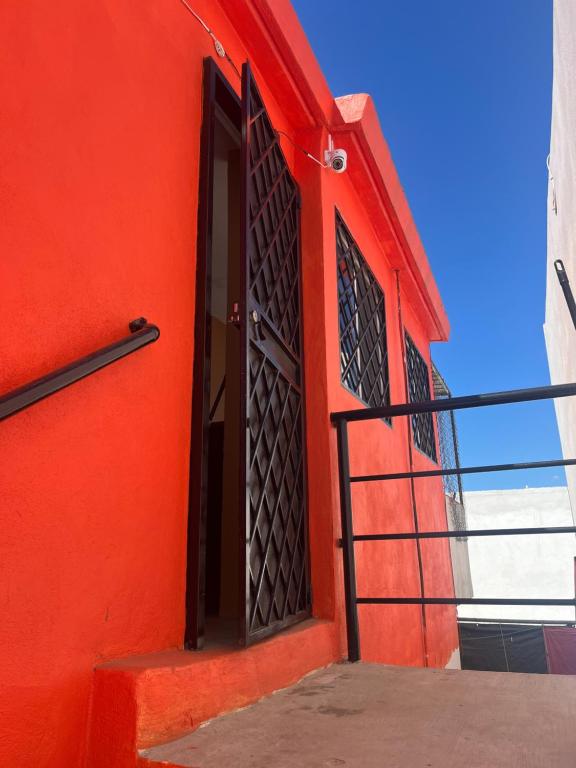 an orange building with a red door and stairs at Casa de chapis in Ensenada