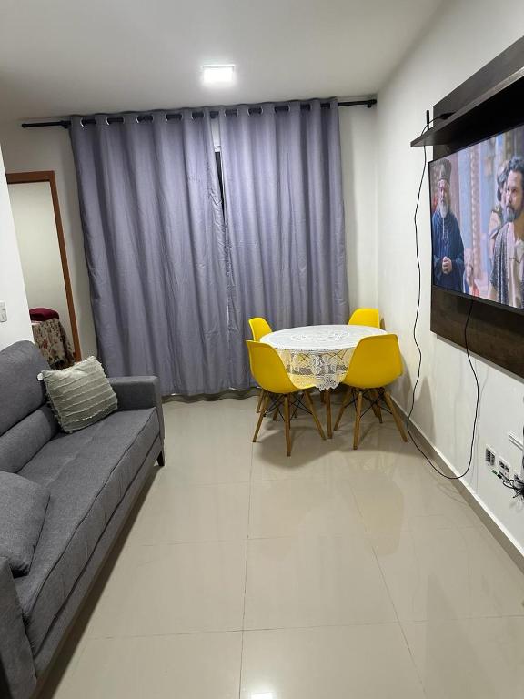 a living room with a couch and a table and a tv at APTO COMPLETO - MORADA DO OURO in Cuiabá