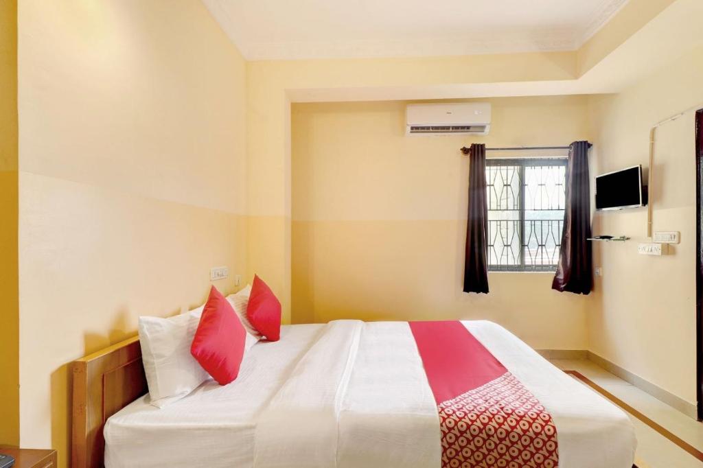 ein Schlafzimmer mit einem großen Bett mit roten Kissen in der Unterkunft OYO Flagship Sunder Nivas in Bangalore