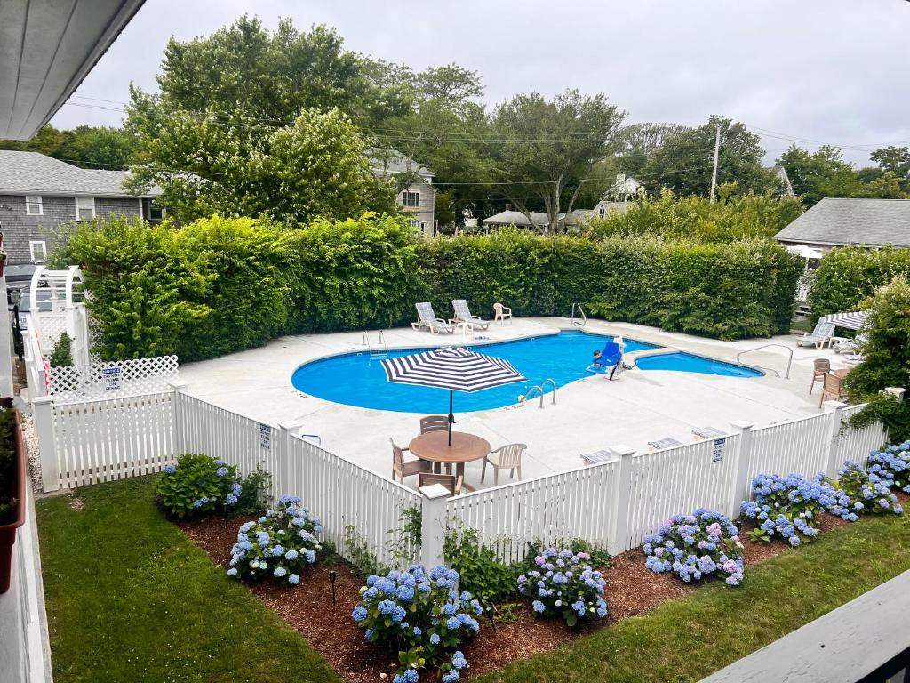 una valla blanca alrededor de una piscina con sombrilla en Edgartown Commons Vacation Apartments en Edgartown