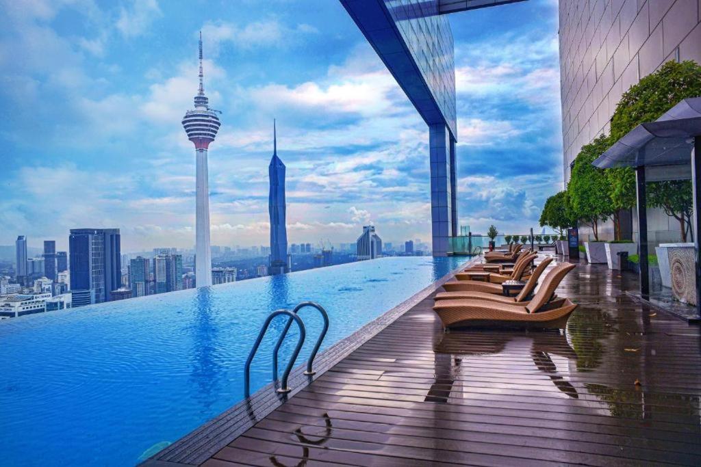a row of chairs sitting on the edge of a swimming pool at The Platinum Serviced Suites by Faced in Kuala Lumpur