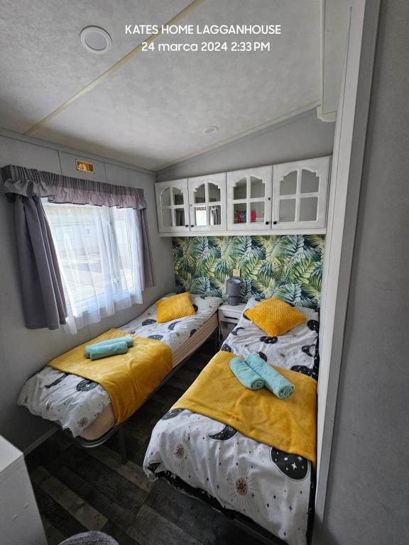 2 letti in una camera con lenzuola gialle e blu di Kates Home Lagganhouse Woodland Way 19 a Ballantrae