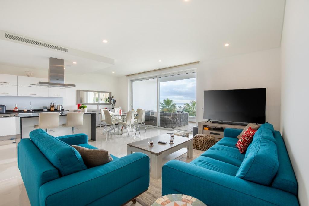 a living room with two blue couches and a tv at Casa Lilou - Luxury Oceanview Penthouse in Lagos
