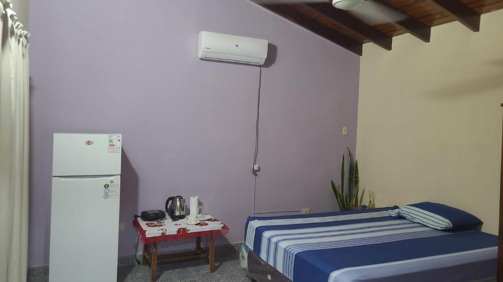 a room with a bed and a refrigerator and a table at Hostal Ña Lali in Villarrica