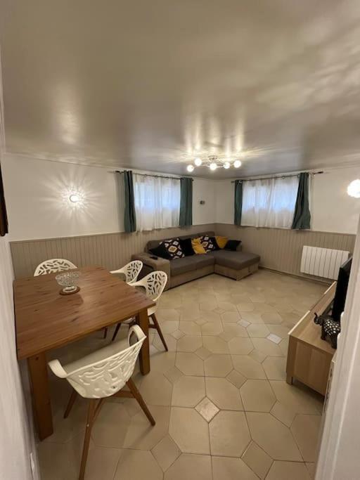 uma sala de estar com uma mesa e cadeiras e um sofá em Appartement dans petite résidence très calme em Drancy