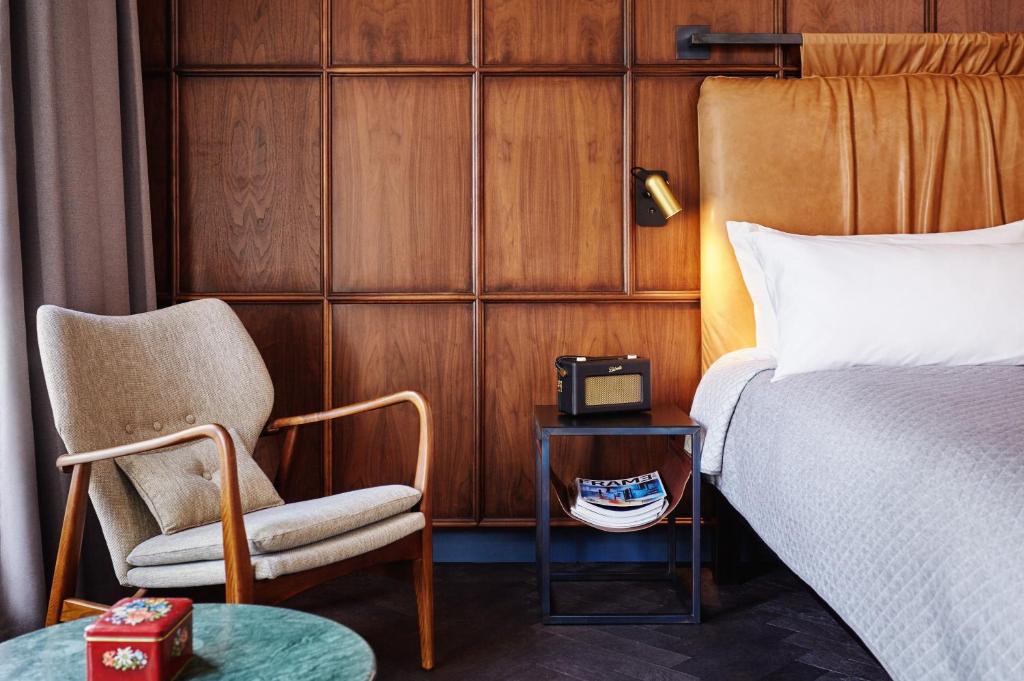 a bedroom with a bed and a chair and a table at The Hoxton, Amsterdam in Amsterdam