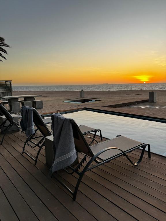 two chairs and a table on a deck with the beach at Dolphin Beach Villa in Rand Rifles