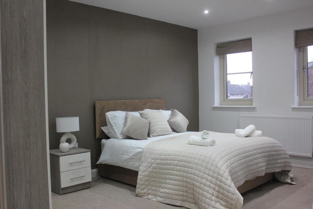 a bedroom with a bed with white sheets and a window at Brook Meadow House, 4 bed house, Manchester in Astley