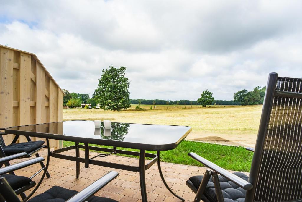 eine Terrasse mit einem Tisch, Stühlen und einem Feld in der Unterkunft Ferienhaus "Felix" in Korswandt