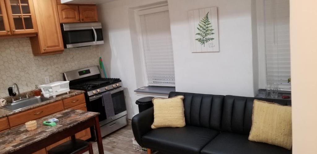 a living room with a black couch in a kitchen at A cozy quiet place to be at peace in Wakefield