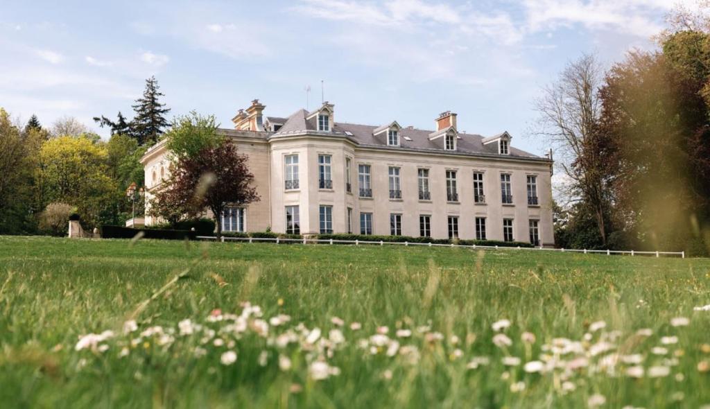 ein großes weißes Haus mit einem Grasfeld davor in der Unterkunft Hôtel Chateau de Maffliers - Demeures de Campagne in Maffliers