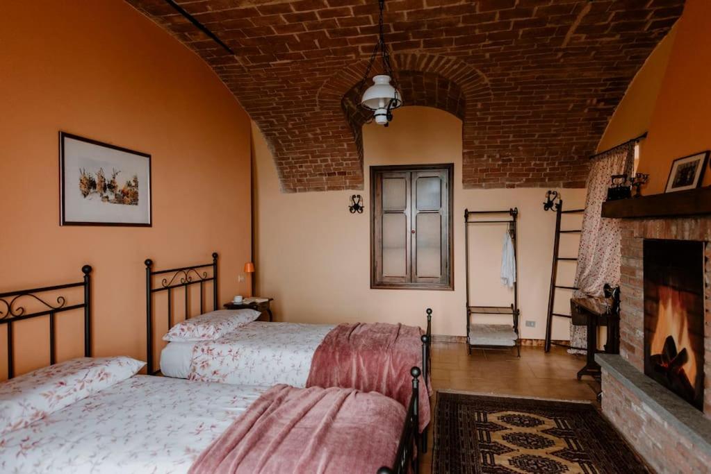 1 dormitorio con 2 camas y chimenea en Sky & Vineyards - Melograno - en La Morra