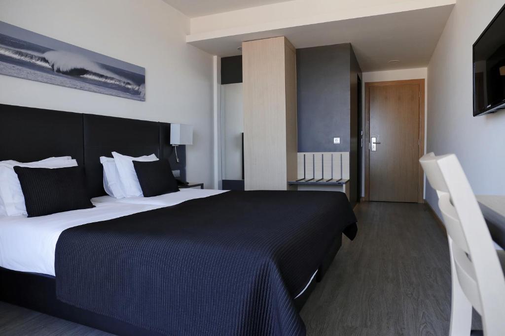 um quarto com uma cama grande e um cobertor preto em Hotel M em Espinho