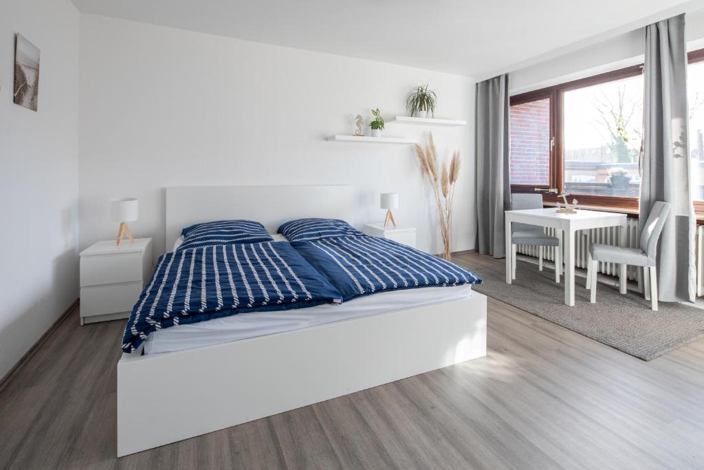 a white bedroom with a bed with blue pillows at Biebrach's Ferienwohnungen in Wilhelmshaven