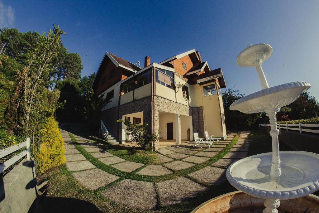 uma casa grande com duas estátuas em frente em Cerejeira Guest House em Campos do Jordão