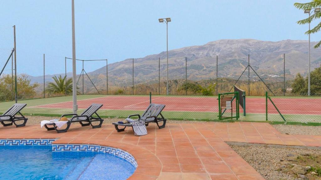 - un court de tennis avec trois chaises et une piscine dans l'établissement Villa Bandoleros Arenas by Ruralidays, à Arenas