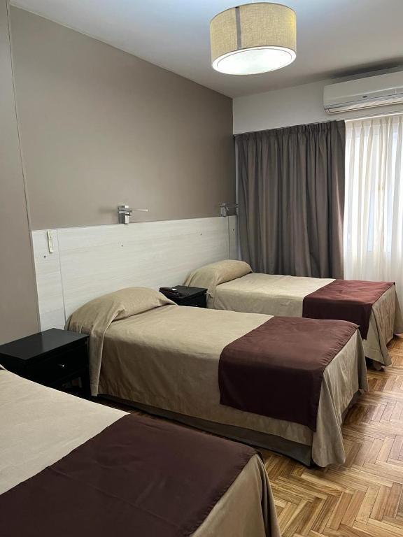 Cette chambre comprend deux lits et une grande fenêtre. dans l'établissement Columbia Palace Hotel, à Buenos Aires