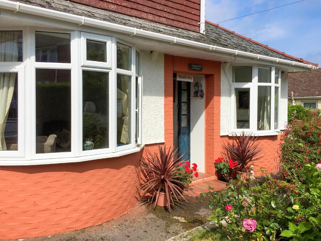 a red and white house with a white window at Ewenny Cottage in Bridgend