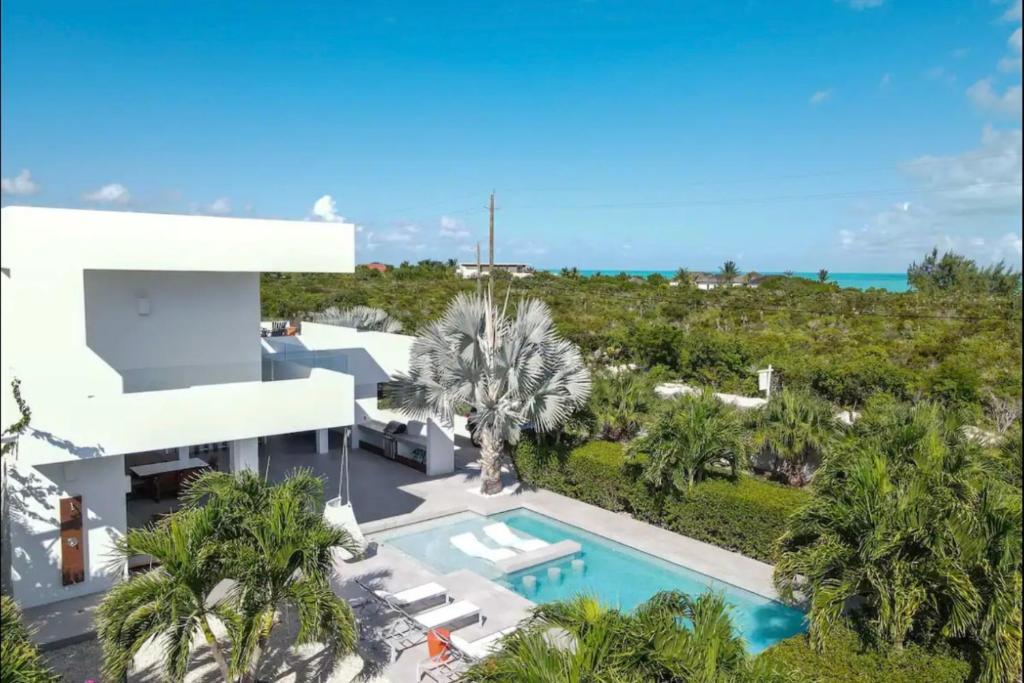 Long Bay HillsにあるEntire Villa in Providenciales, Long Bay Beach, Turks and Caicos Islandsのヤシの木とスイミングプールのある家の空中を望む