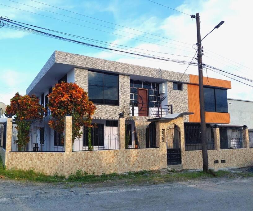 une maison en briques avec une clôture devant elle dans l'établissement Amplio y cómodo departamento con garaje., à Puyo