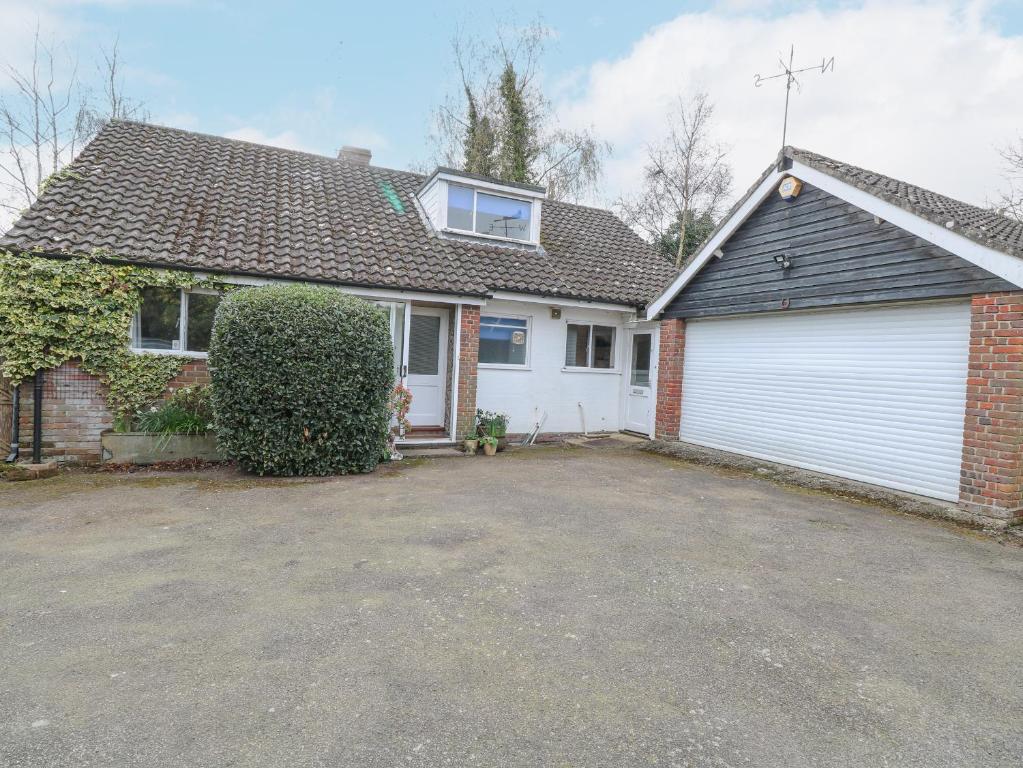 a house with a garage and a white garage door at Swan Dyke Cottage in Horning
