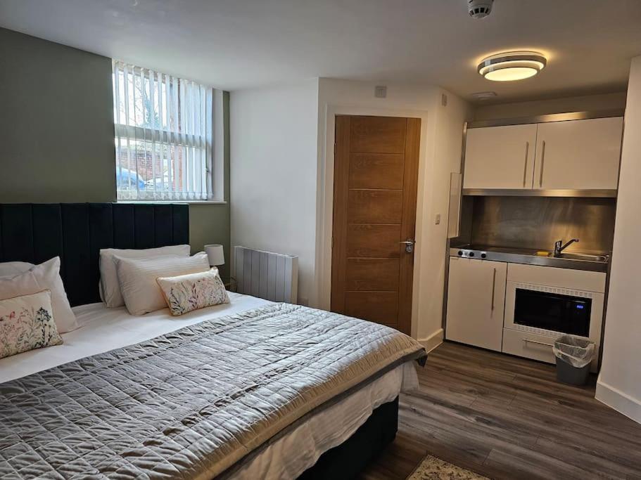 a bedroom with a large bed and a kitchen at ZenZone Studio Flat in Preston