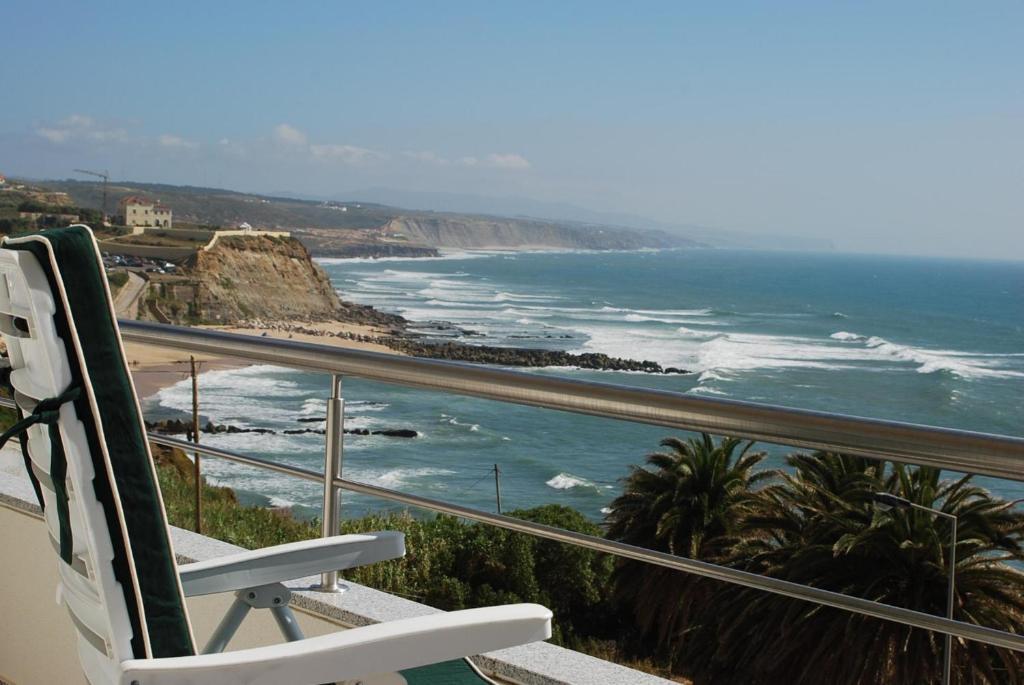 a white chair sitting on a balcony looking at the ocean at Sol no Horizonte - AT in Ericeira