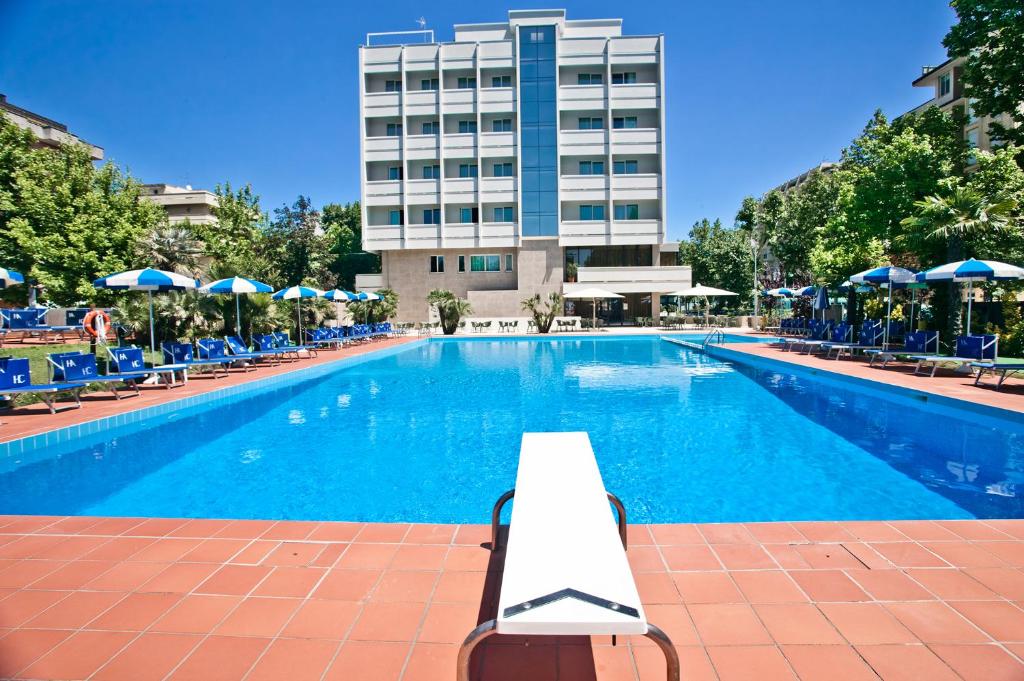 a swimming pool with chairs and a building in the background at Hotel Ambasciatori in Cesenatico