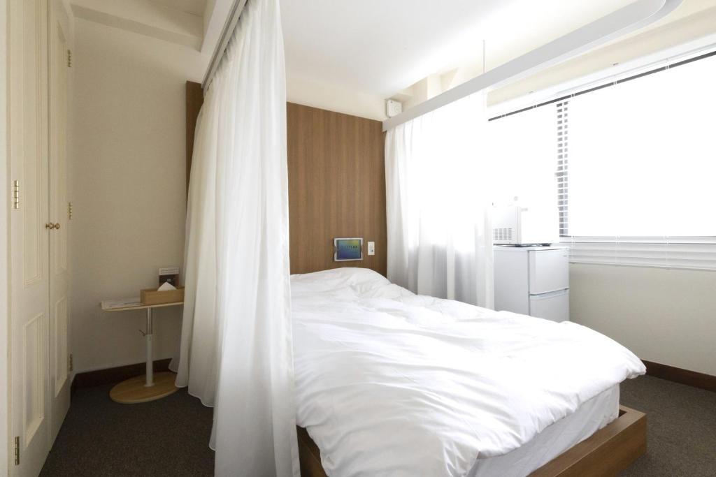 una camera da letto con un letto con lenzuola bianche e una finestra di SLEEPLAB 高輪 -睡眠特化型Hotel- a Tokyo