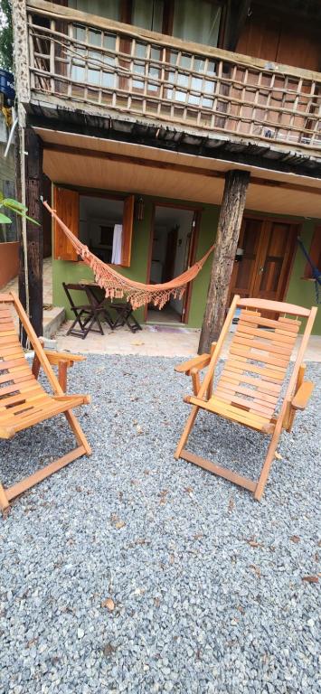 duas cadeiras e uma rede em frente a um edifício em Suítes da Quinta dos Samaniegos em Itaúnas