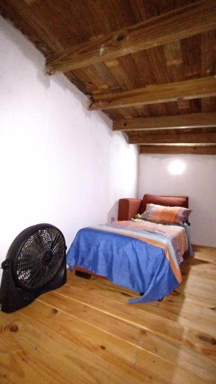 een slaapkamer met een bed en een ventilator op de vloer bij La Casita Quincho in González Catán