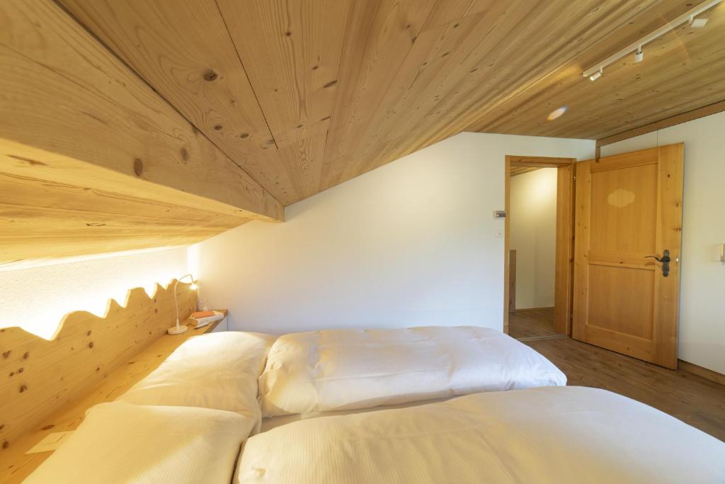 a bedroom with two white beds and a wooden ceiling at Schönau in Unterwasser
