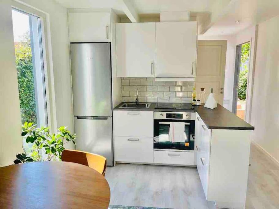 a kitchen with white appliances and a wooden table at Trevlig boende i en gästhuset med gratis parkering in Malmö