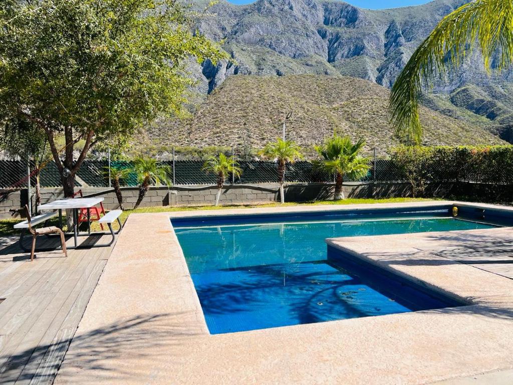 a swimming pool with palm trees and mountains in the background at La huasteca camping con alberca in Monterrey