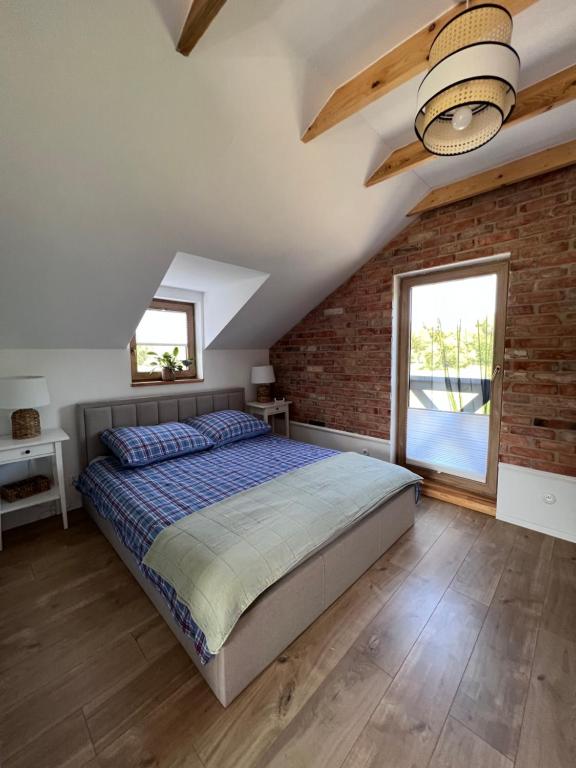 1 dormitorio con cama y pared de ladrillo en Domek pod lasem „2”, en Pasłęk